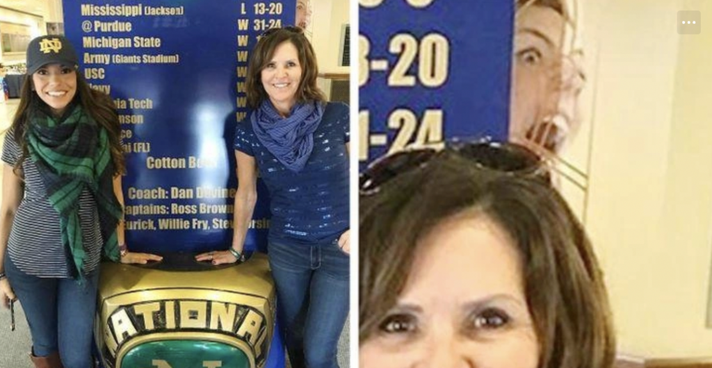 Two women try to take photo in front of basketball stats poster, but a woman makes a strange face through the glass window behind them. 