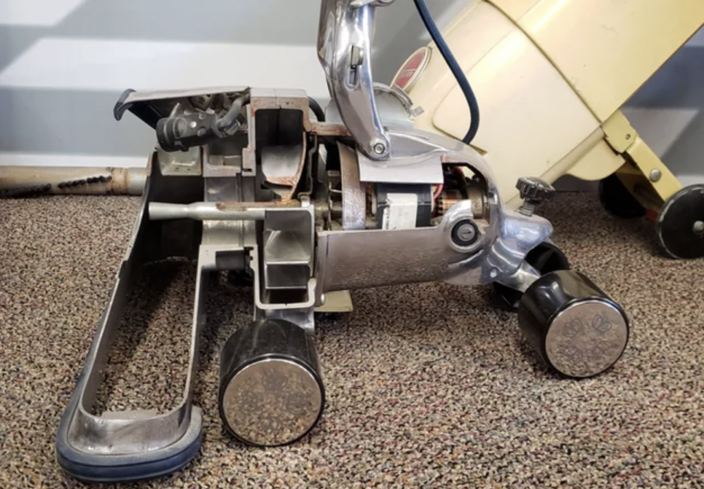 An image of a vintage vacuum cleaner that's been cut in half. 