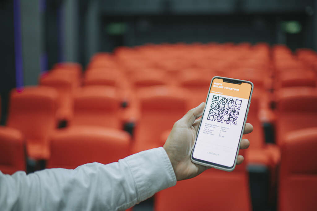 Close-up image of someone extending their phone to show off their virtual concert ticket. 