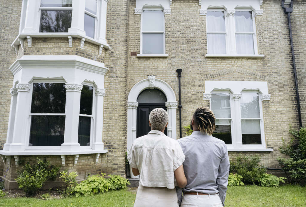 Image of a couple standing out front of what looks to be a beautiful home in London. 