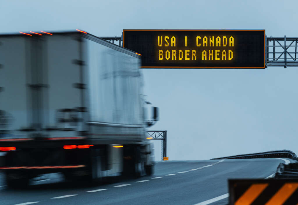 A highway poster of the USA / Canada border being up ahead. 