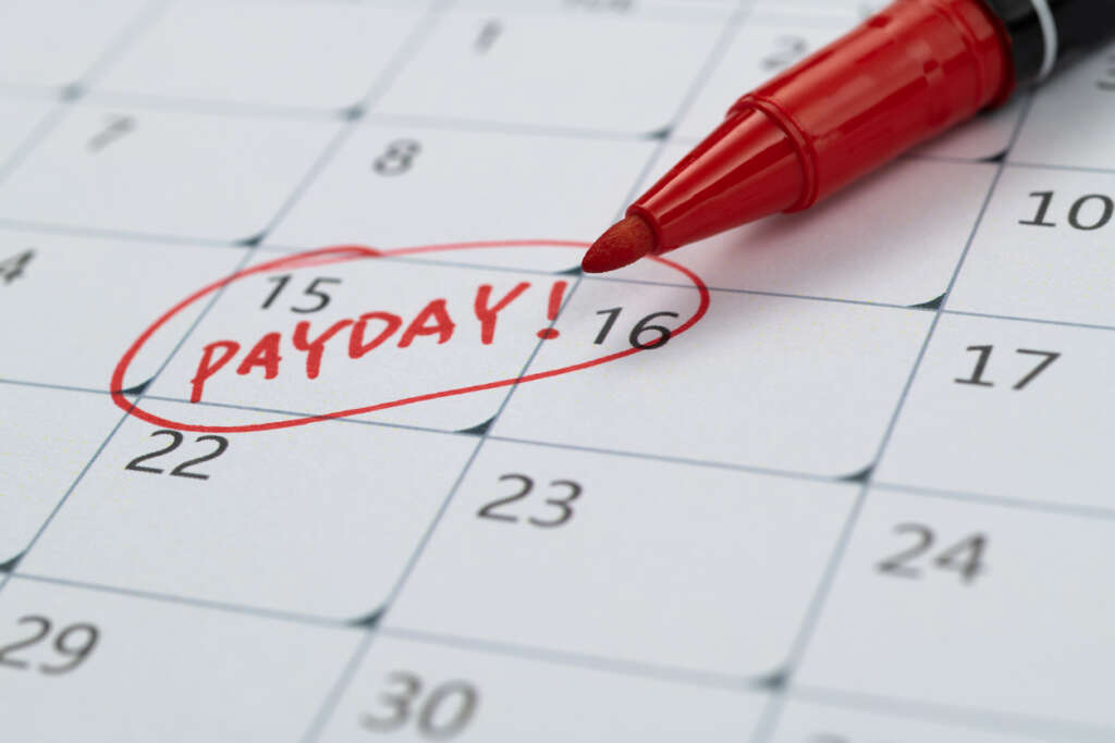 A red pen with "payday" that's been circled on a calendar. 