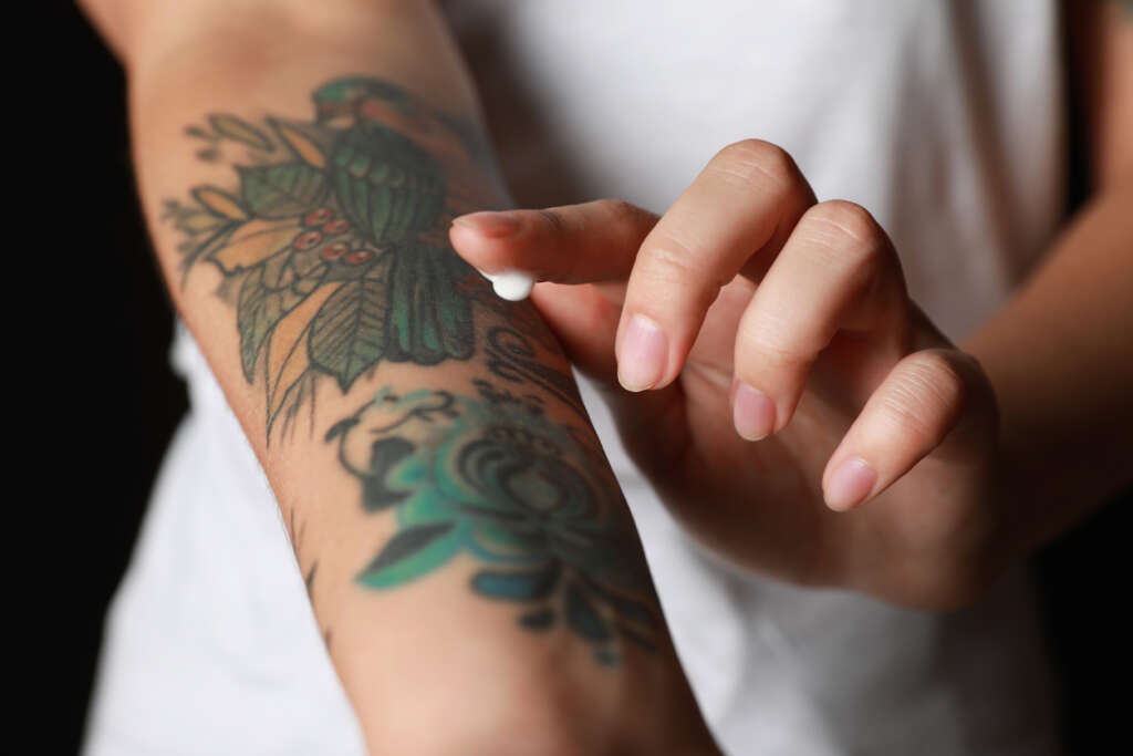 Image of a person applying tattoo cream to their new forearm tattoo. 