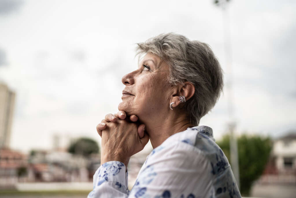 Elderly woman, smiling while staring up at the sky and contemplating. 