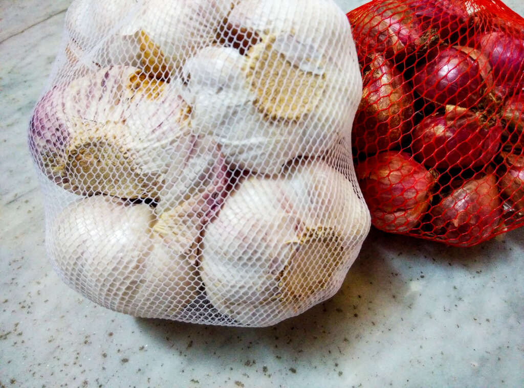 A couple of filled mesh onion bags that have been placed next to each other. 