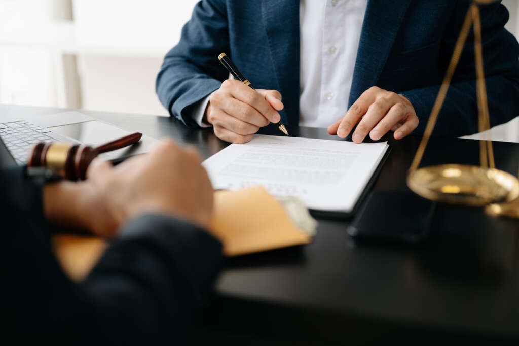 Image of a lawyer using a nice pen to sign off on a document at their desk. 