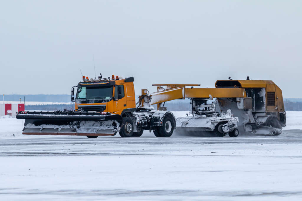A snow sweeper that is trying to clear off a snowy runway. 