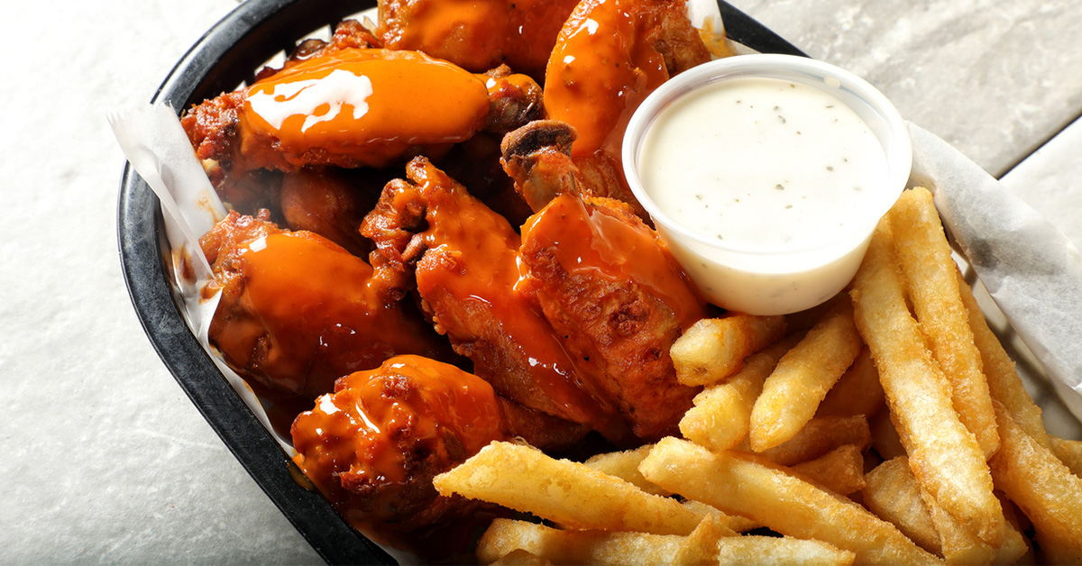 An image of wings and fries in a basket.