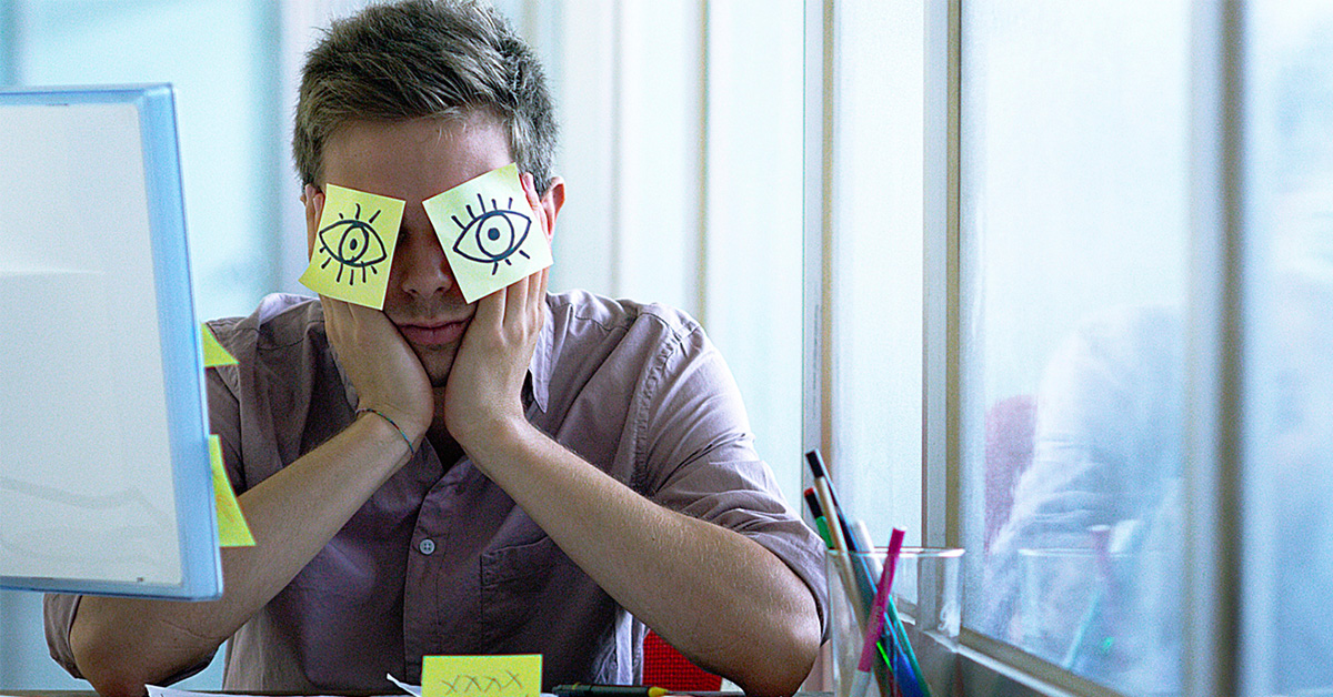 An image of a young employee with sticky notes on his face.