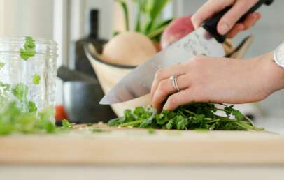 An image of someone cutting herbs with a chef's knife.