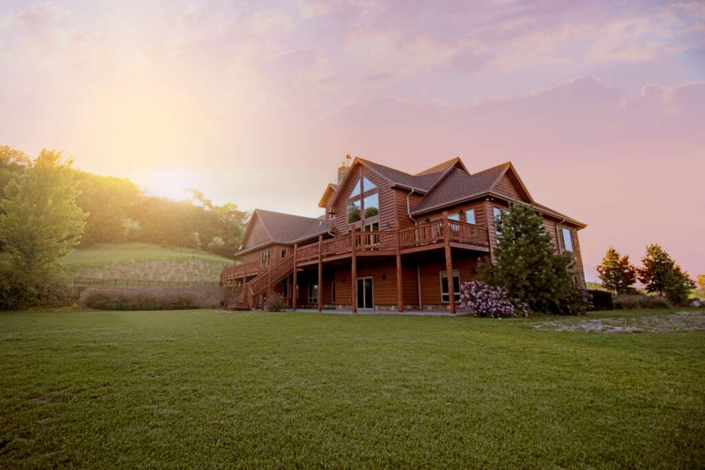 An image of a nice home with the sun setting in the background over a hill. 