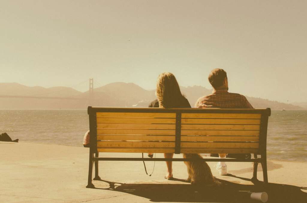 A couple sitting next to each other while in a silent argument and turned away from each other. 