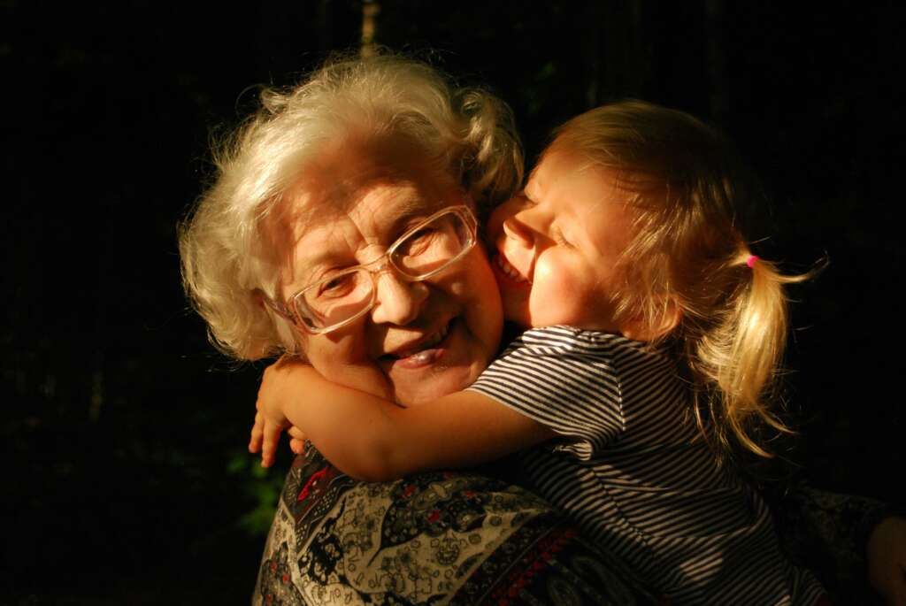 An image of an older woman holding her granddaughter. 
