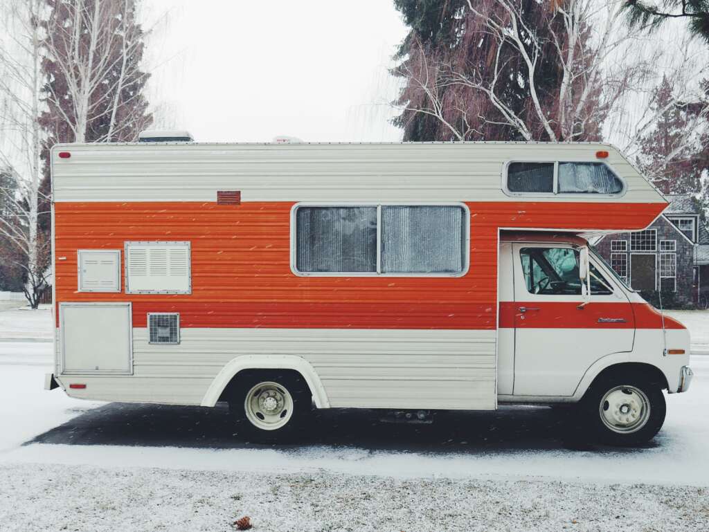 An image of a white RV with an orange line painted on it. 