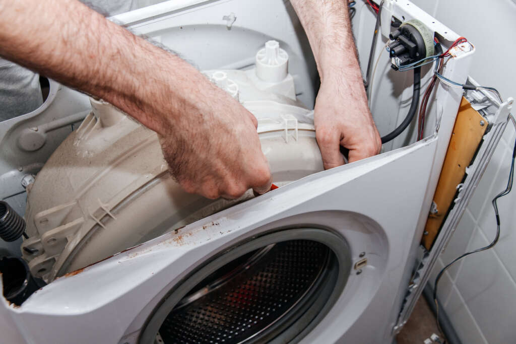 An image of someone fixing their washing machine themselves. 