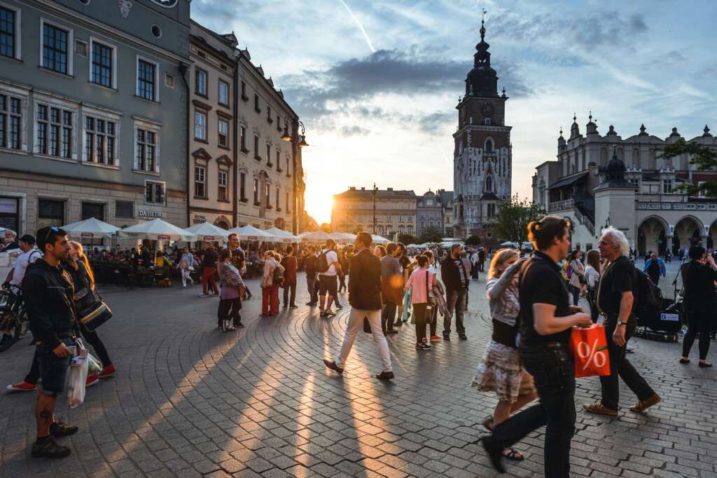 A beautiful image of a sunlit crowded European square with people walking around. 