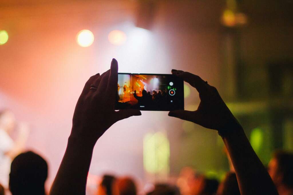 An image of someone holding their phone up while at a concert. 