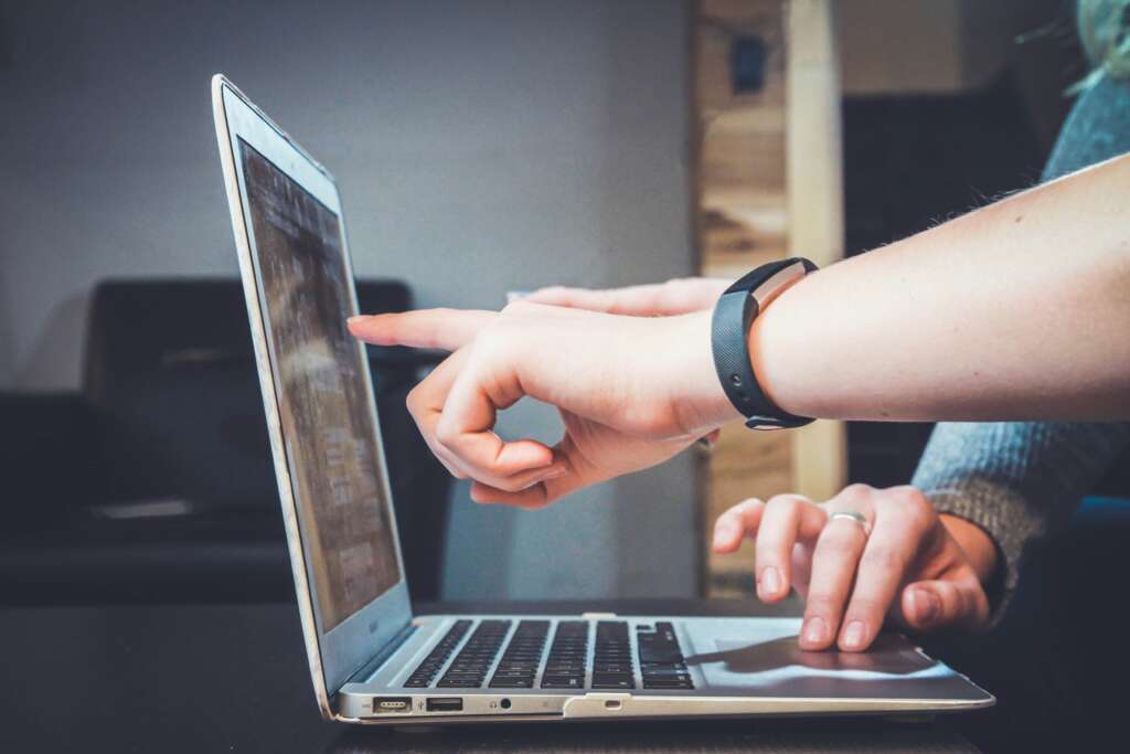 A person pointing at a laptop screen. 