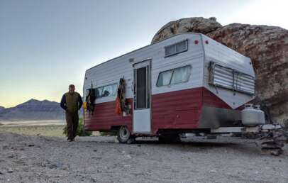 An image of a man walking away from his RV when parked in the desert.