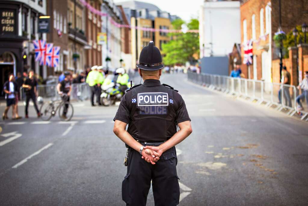 An image of a police officer with their back turned and arms crossed behind their back. 