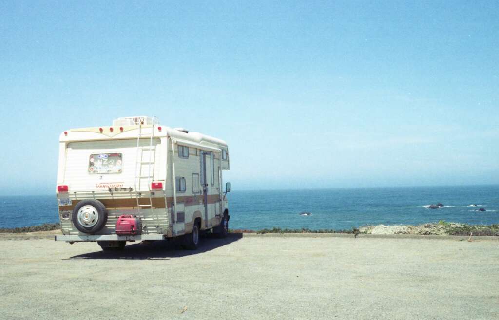 An image of an RV parked in front of a view of the ocean. 