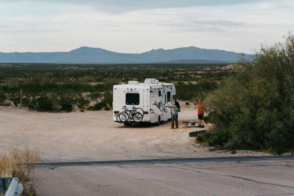 An image of an RV pulled over on a desert road. 