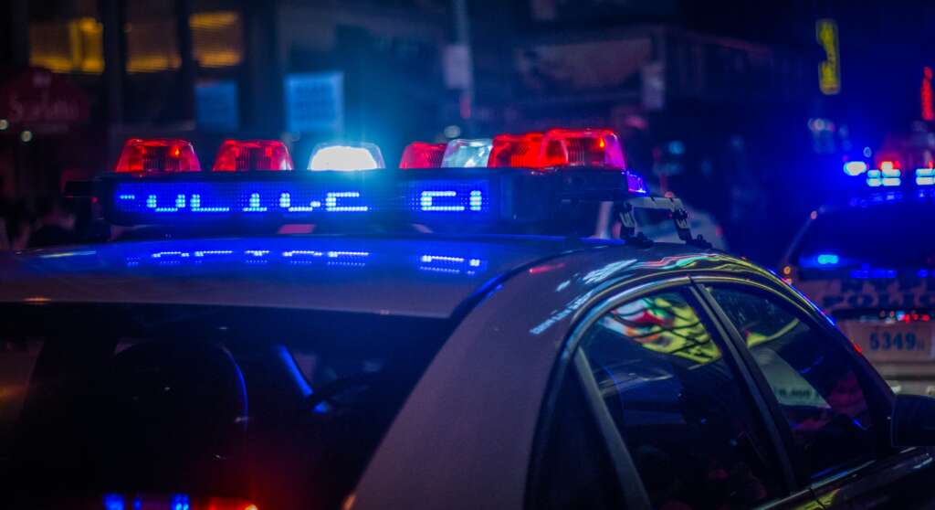 An image of a police car with lights lit up on the roof of the car. 