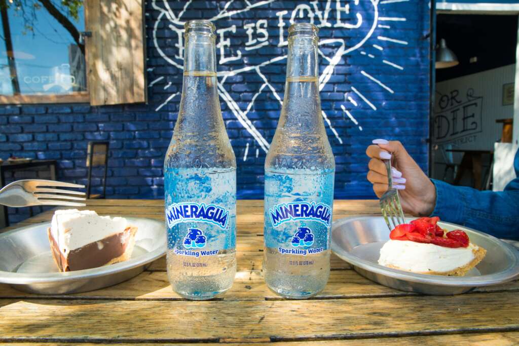 A couple of glass bottles of Mineragua placed next to each other on a wooden table. 