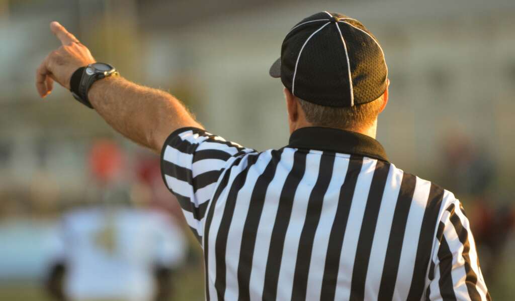 A close-up image of a ref making a call during a game. 