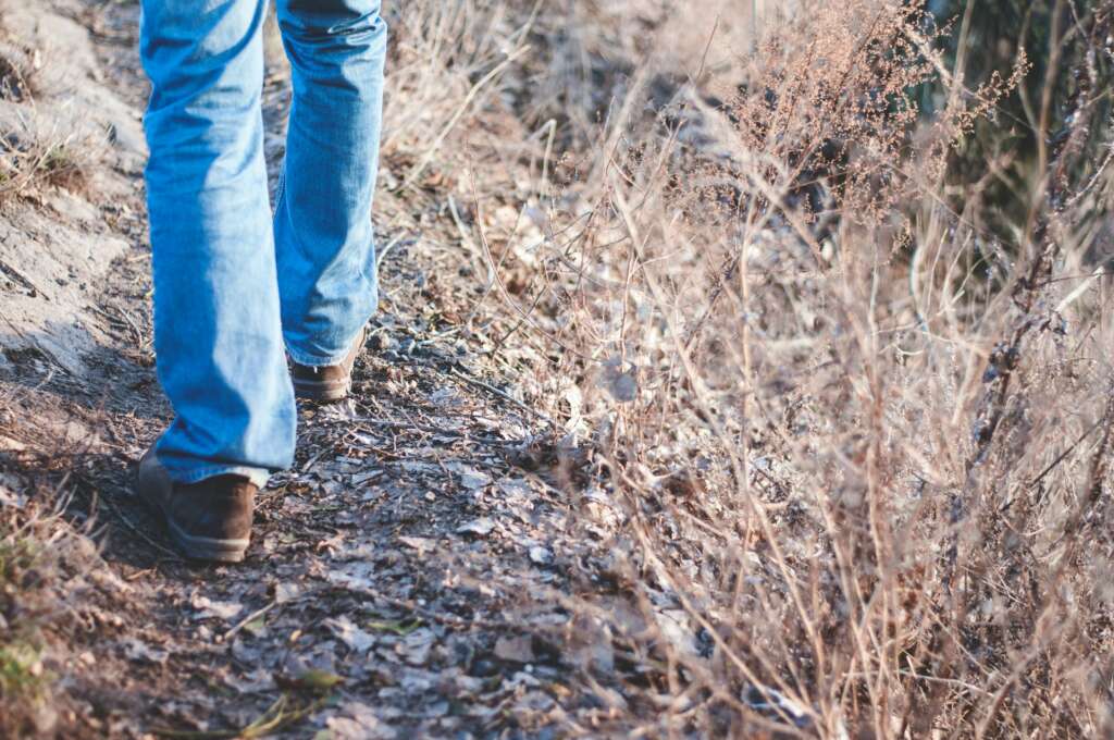 An image of a person walking on a trail with jeans on. 