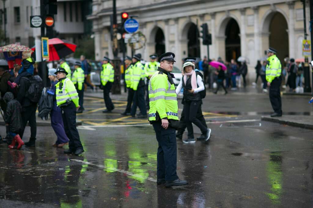 A group of British police officers outside on a rainy day. 
