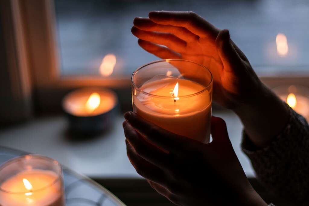 An image of someone holding their hand over a burning candle. 