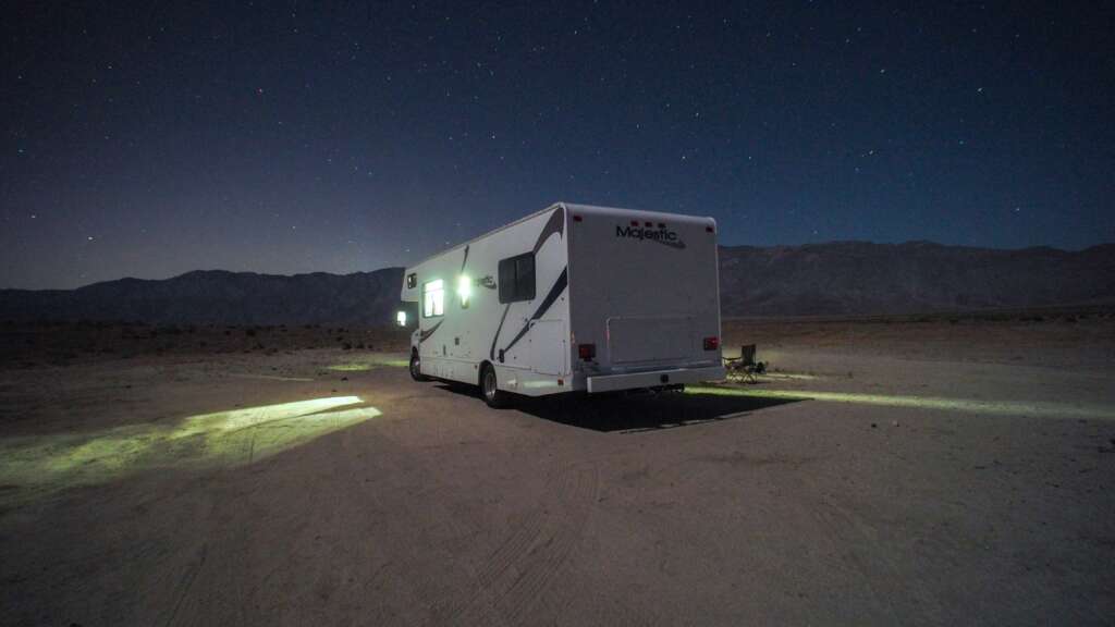 An image of an RV parked in a desert at night. 