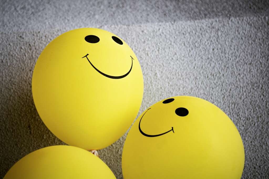 An image of yellow-colored balloons with smiley faces on them. 