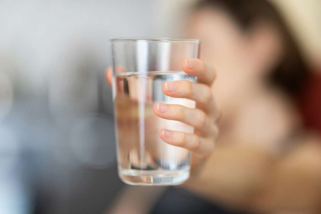 An image of someone holding up a water cup with a blurred background. 