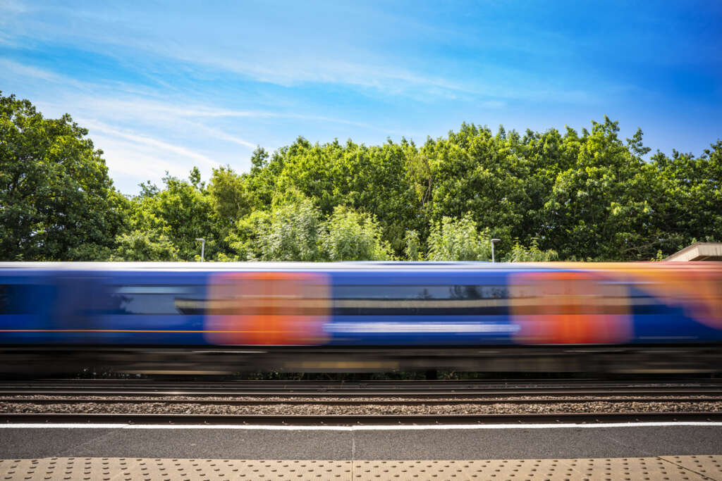 An image of a train racing by on a sunny day. 