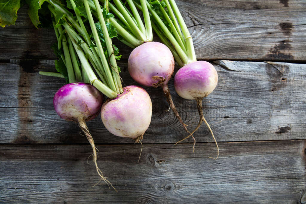 An image of turnips on a wooden table. 