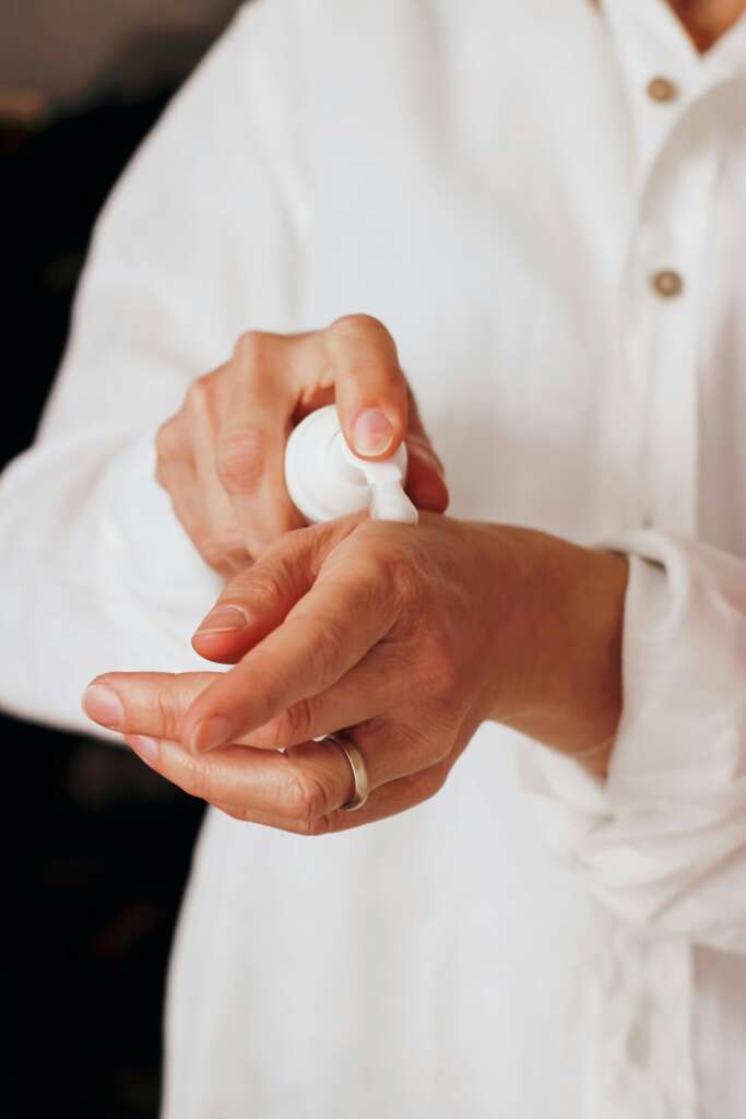 A person using lotion on their left hand. 