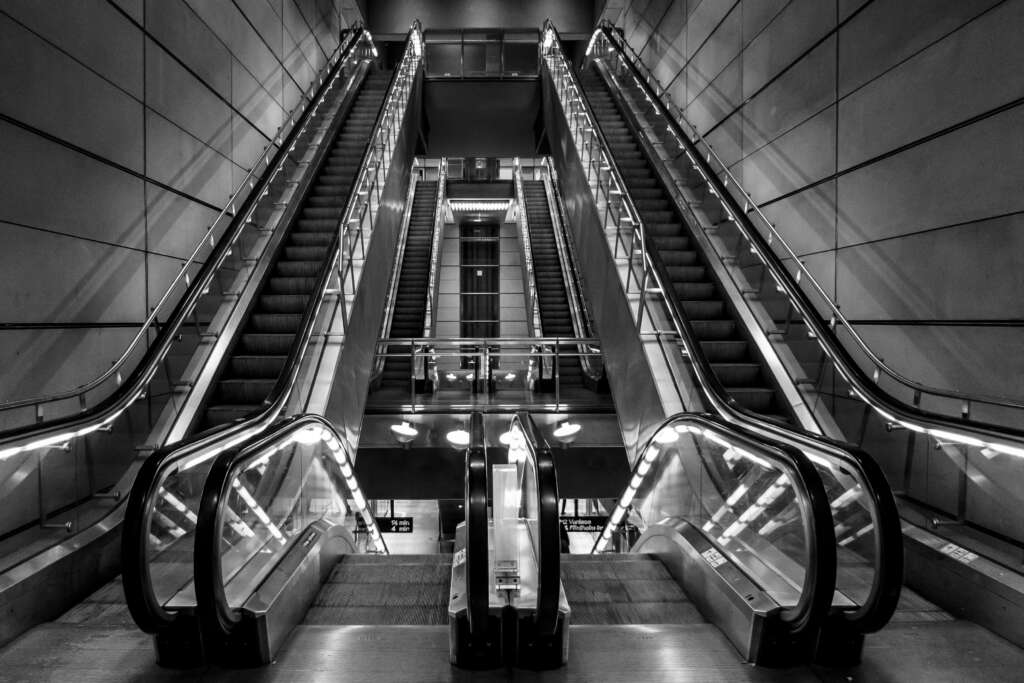 A black and white image of an escalator. 