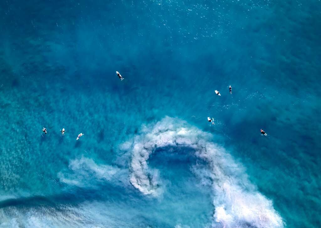 An image of people swimming in bright blue water. 