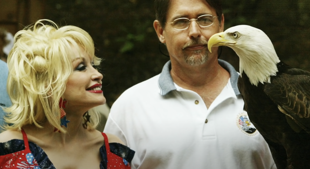 Dolly Parton smiling while looking at bald eagle. 