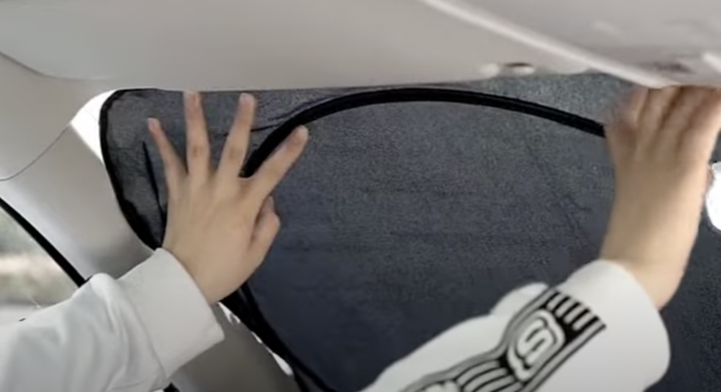 An image of someone putting up their car sunshade. 