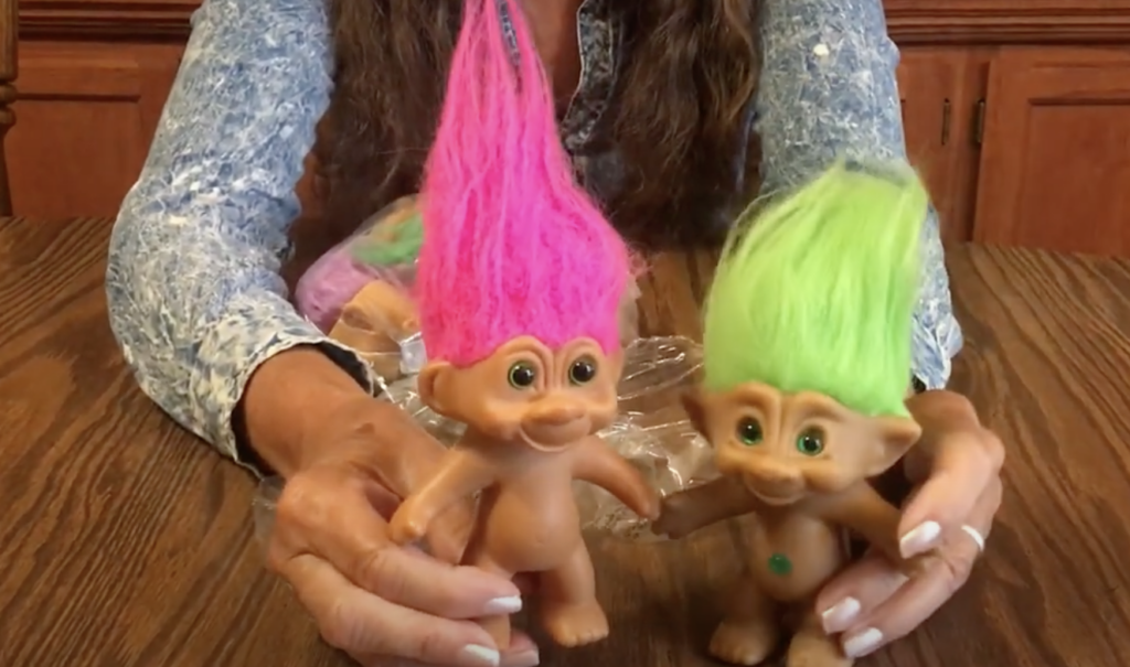 An image of a couple of Troll Dolls with bright pink and bright green hair. 