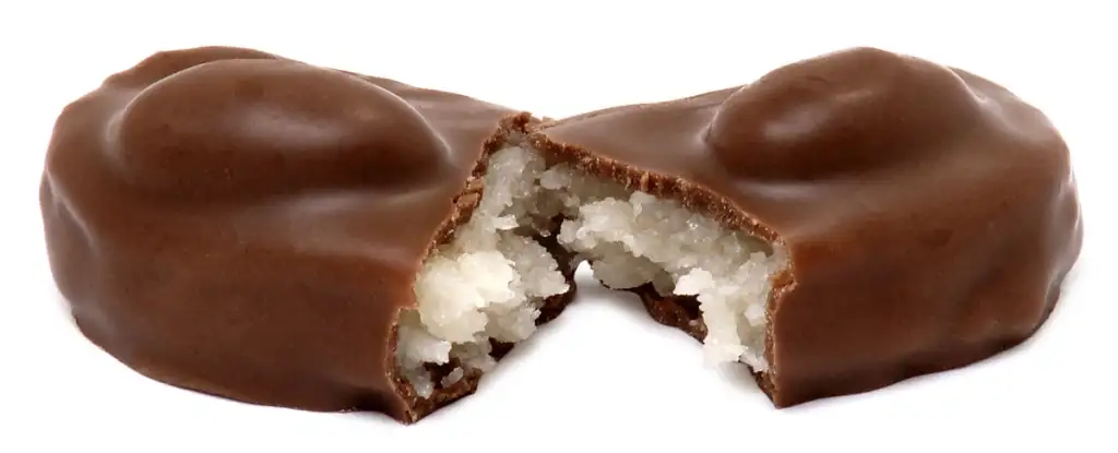 A chocolate-covered candy split in half, revealing a white, coconut-filled center. The chocolate is smooth and slightly shiny, while the coconut filling appears moist and textured.