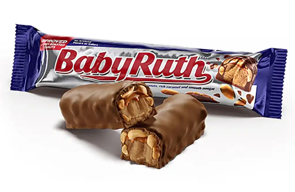 A Baby Ruth candy bar in its wrapper is placed next to two halves of the bar, revealing its interior of caramel, peanuts, and nougat coated in chocolate. The wrapper is silver with red and blue accents, and the text "Baby Ruth" is prominently displayed.