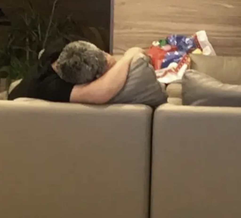 A person with their arm on the couch, but it looks like a couple embracing. 