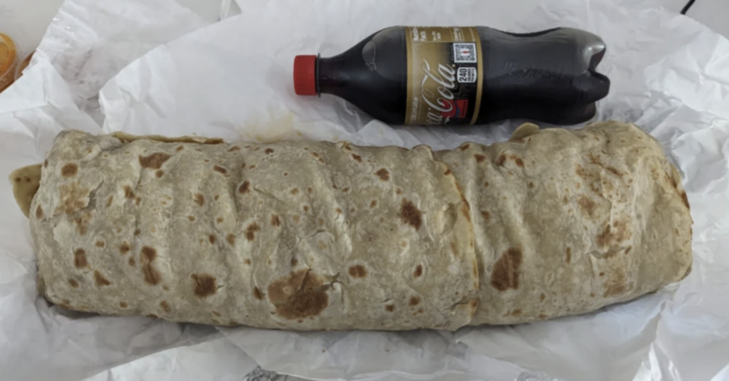 An image of someone's $30 burrito next to a bottle of Coke. 