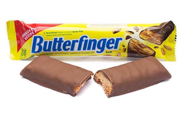 A Butterfinger candy bar sits in its colorful wrapper labeled "Butterfinger" on a white background. Below the wrapper, a chocolate-covered Butterfinger bar is broken in half, revealing its crispy, peanut-buttery interior.