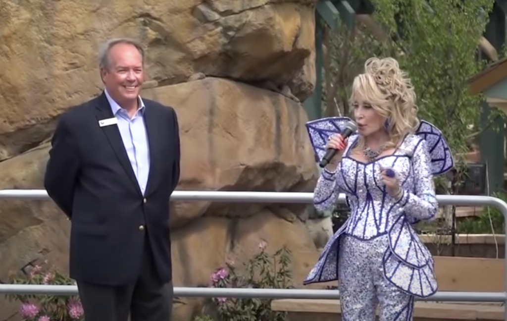 Dolly Parton talking into the mic while at an outdoor exhibit. 