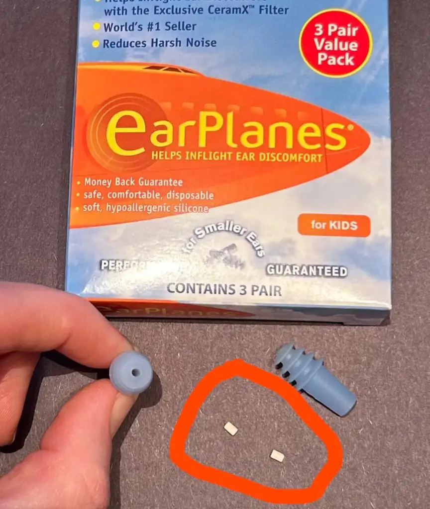 A hand holds an open blue container beside an EarPlanes box labeled "for KIDS." The box highlights features like CeramX filter and hypoallergenic silicone. Three small white items are circled in red next to the container.